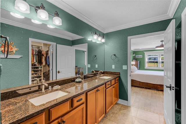 ensuite bathroom featuring crown molding, a textured wall, a sink, and ensuite bath