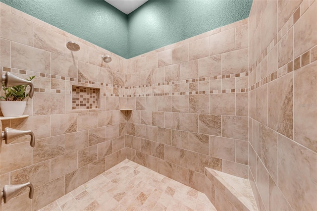 full bath with a tile shower and a textured wall