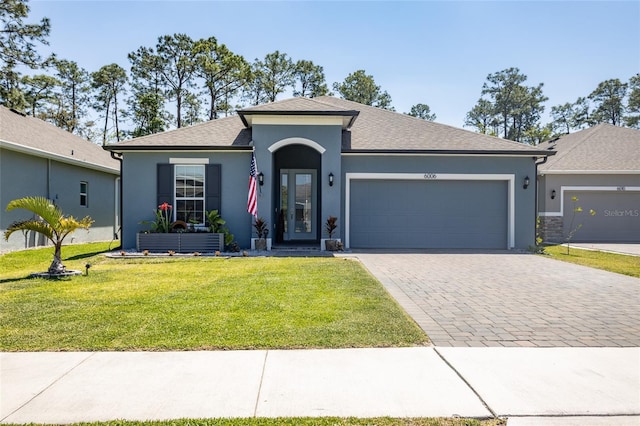 ranch-style house featuring roof with shingles, stucco siding, decorative driveway, an attached garage, and a front yard