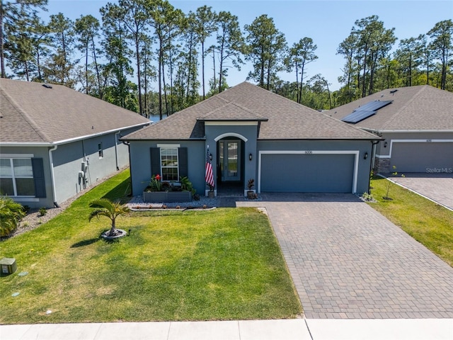 ranch-style home featuring an attached garage, roof with shingles, stucco siding, and a front lawn