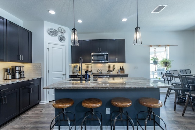 kitchen featuring tasteful backsplash, visible vents, stainless steel microwave, and dark wood-style floors