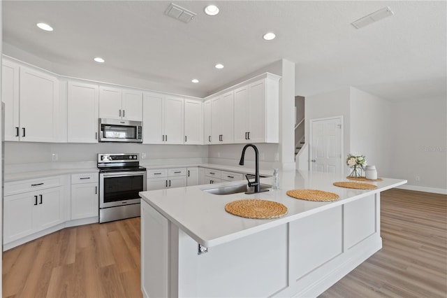 kitchen with light wood-type flooring, a sink, visible vents, and stainless steel appliances