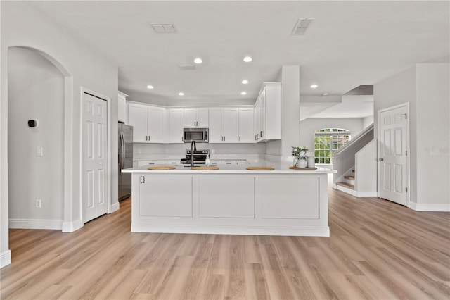 kitchen with light countertops, appliances with stainless steel finishes, baseboards, and a peninsula