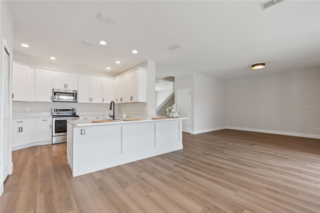 kitchen with appliances with stainless steel finishes, light wood-type flooring, open floor plan, and visible vents