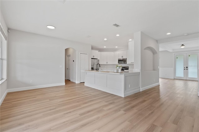 kitchen with visible vents, open floor plan, arched walkways, light countertops, and appliances with stainless steel finishes