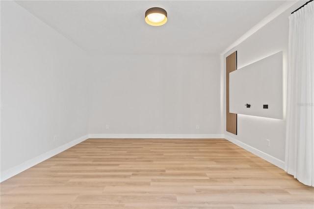 spare room featuring baseboards and light wood-style floors