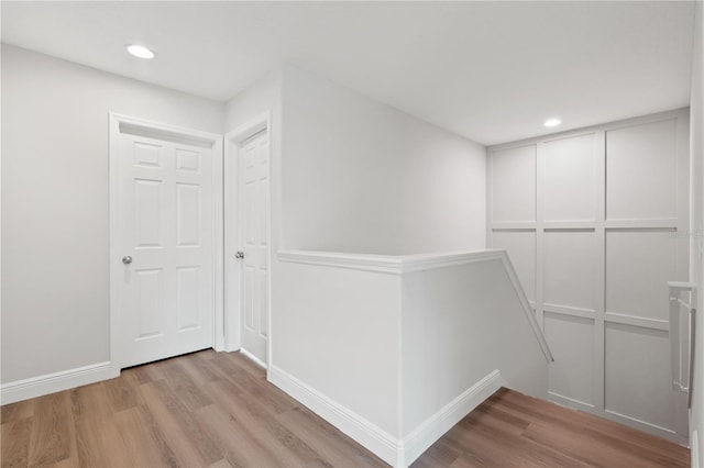 hallway featuring recessed lighting, an upstairs landing, and light wood-style floors