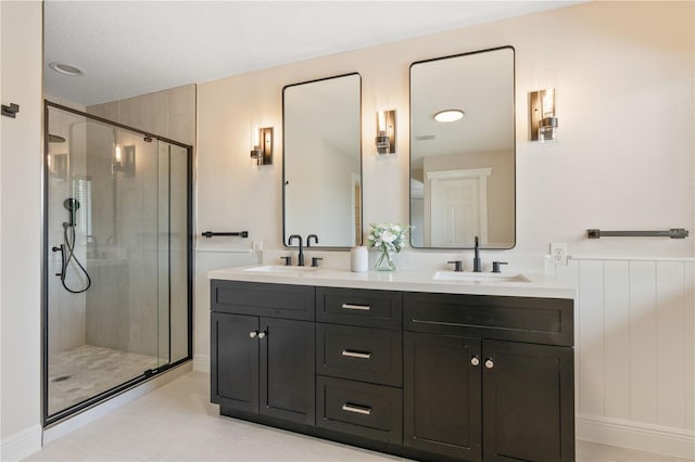 bathroom with double vanity, a shower stall, and a sink