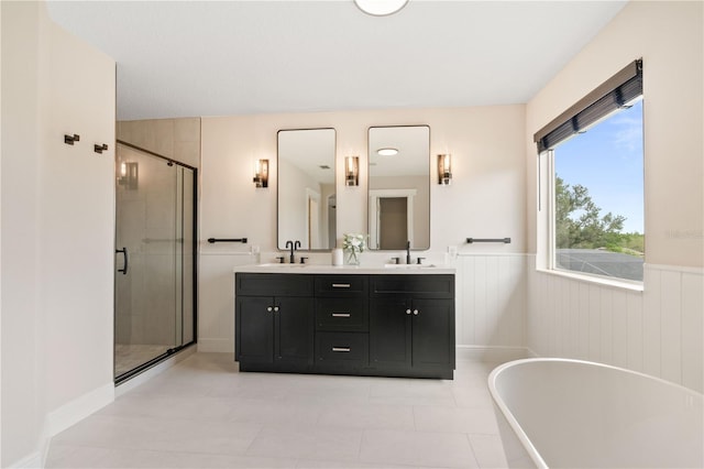 full bathroom with a sink, wainscoting, a soaking tub, and a shower stall