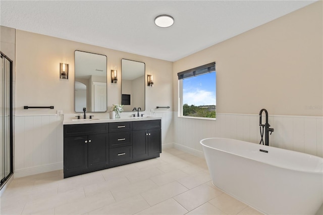 full bath with wainscoting, a freestanding bath, double vanity, and a sink