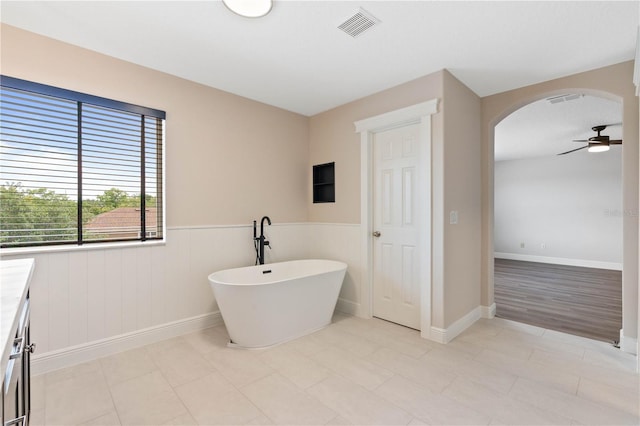 bathroom featuring baseboards, wainscoting, ceiling fan, visible vents, and a freestanding tub
