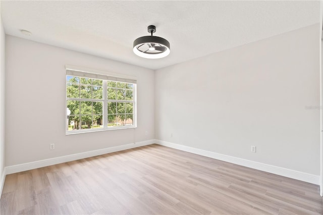 spare room with baseboards and light wood-style flooring