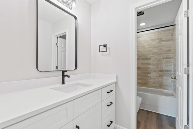 bathroom featuring toilet, bathing tub / shower combination, wood finished floors, and vanity
