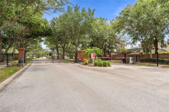 view of road featuring traffic signs, curbs, a gated entry, and a gate