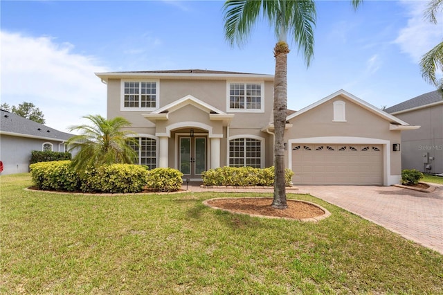 view of front facade featuring french doors, a garage, stucco siding, decorative driveway, and a front yard