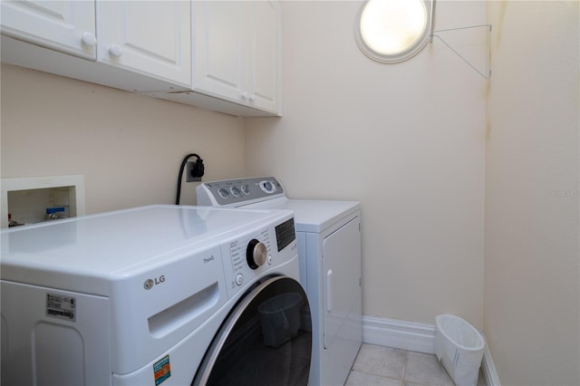 laundry area with baseboards, independent washer and dryer, light tile patterned floors, and cabinet space