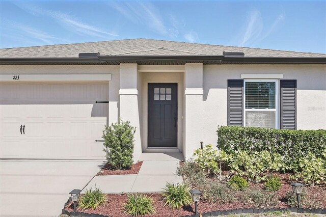 223 Courtland Blvd, Deltona, FL 32738 - view of exterior entry featuring concrete driveway, roof with shingles, stucco siding, and an attached garage