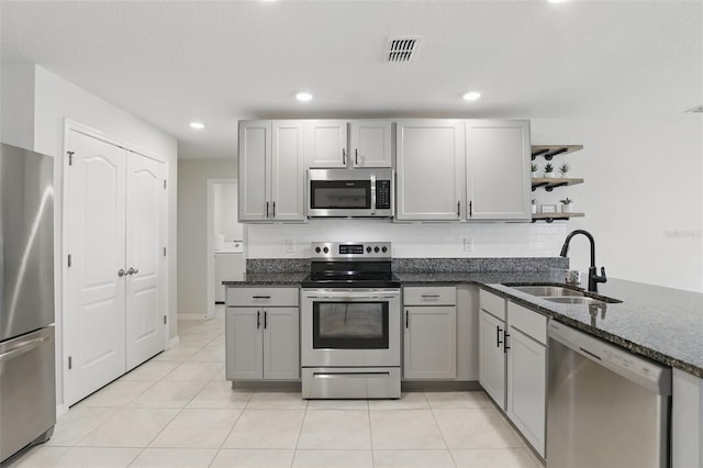 223 Courtland Blvd, Deltona, FL 32738 - kitchen with light tile patterned floors, open shelves, a sink, appliances with stainless steel finishes, and dark stone counters