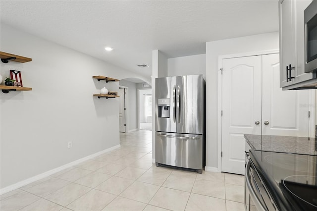 223 Courtland Blvd, Deltona, FL 32738 - kitchen featuring dark stone countertops, open shelves, light tile patterned flooring, stainless steel appliances, and arched walkways