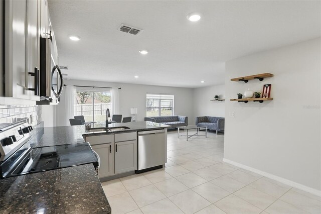 223 Courtland Blvd, Deltona, FL 32738 - kitchen with dark stone countertops, visible vents, a sink, open floor plan, and appliances with stainless steel finishes
