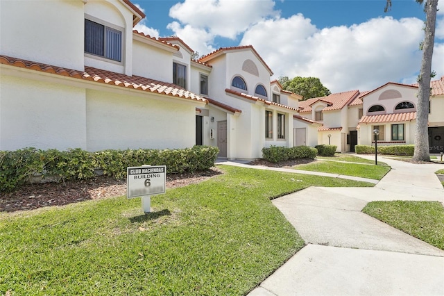 view of front facade featuring a tiled roof, stucco siding, and a front lawn