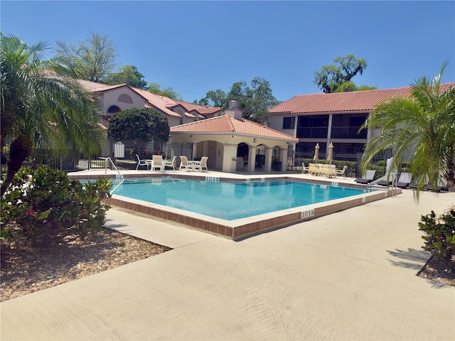 pool with a patio area and fence