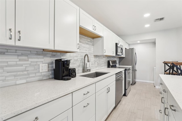 kitchen featuring baseboards, white cabinetry, visible vents, stainless steel appliances, and a sink