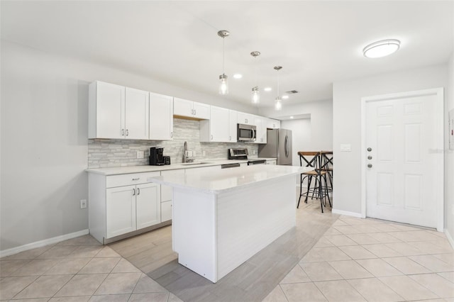 kitchen featuring light tile patterned floors, tasteful backsplash, white cabinets, appliances with stainless steel finishes, and a sink