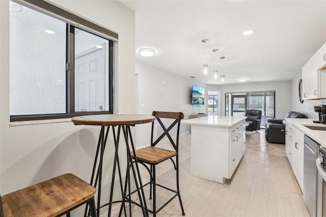 kitchen featuring light countertops, a center island, white cabinetry, and stainless steel dishwasher