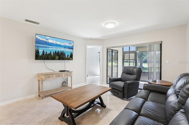 living room with light tile patterned floors, visible vents, and baseboards