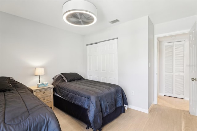 bedroom featuring a closet, visible vents, light wood-type flooring, and baseboards