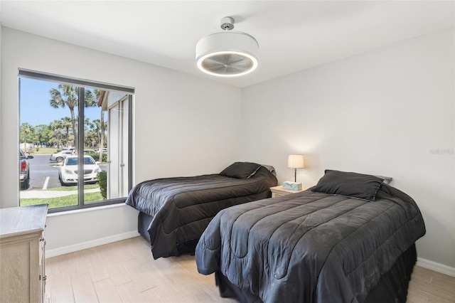 bedroom featuring baseboards, multiple windows, and light wood-style floors