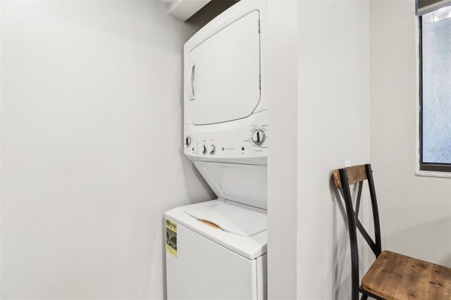 clothes washing area featuring stacked washer and dryer and laundry area