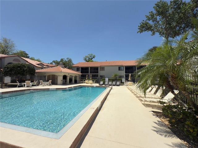 community pool with a patio area and fence