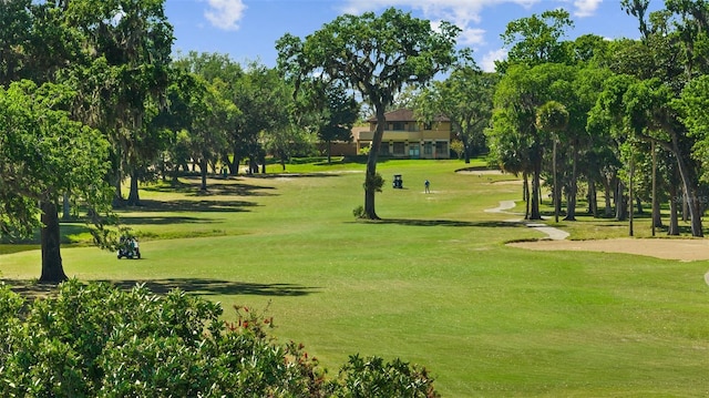view of property's community with view of golf course and a lawn