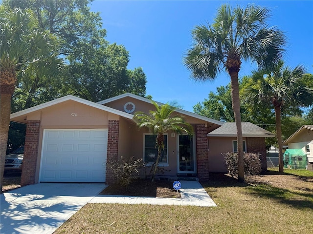 single story home featuring concrete driveway, stucco siding, a front yard, brick siding, and a garage