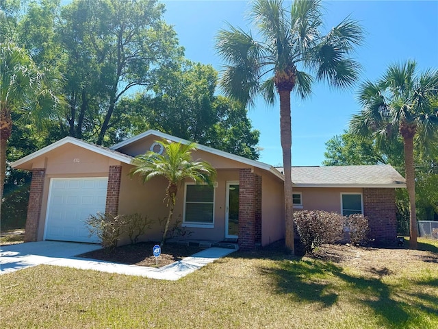 ranch-style home featuring a front yard, a garage, stucco siding, brick siding, and driveway