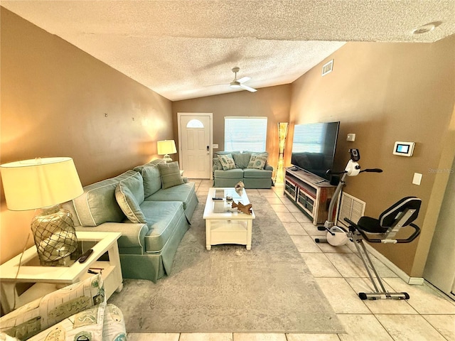 living room featuring ceiling fan, a textured ceiling, visible vents, light tile patterned flooring, and lofted ceiling