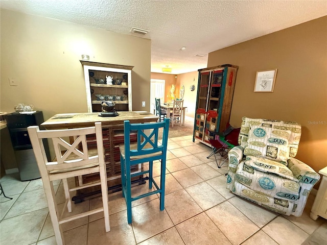 dining room featuring light tile patterned floors, visible vents, and a textured ceiling