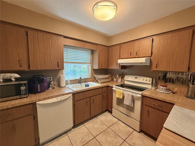 kitchen featuring under cabinet range hood, white appliances, light countertops, and a sink
