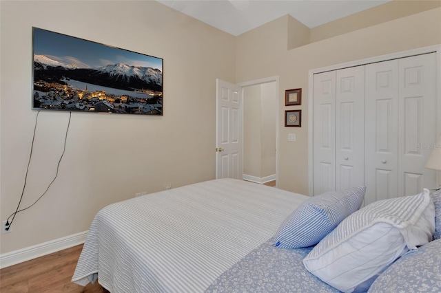 bedroom with baseboards, wood finished floors, and a closet