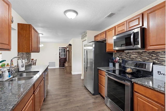 732 Mockingbird Ln, Deland, FL 32720 - kitchen with visible vents, appliances with stainless steel finishes, a sink, brown cabinets, and decorative backsplash