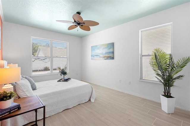 bedroom featuring light wood-style floors, a ceiling fan, and baseboards