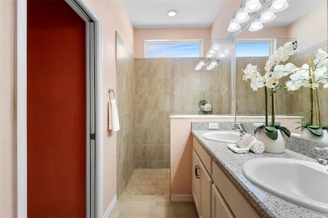 full bath with tile patterned flooring, double vanity, a sink, and a walk in shower