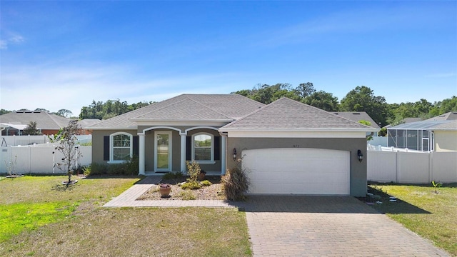 view of front of home featuring an attached garage, a front lawn, stucco siding, and fence