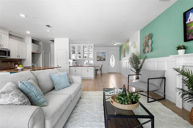 living area with recessed lighting, a wainscoted wall, visible vents, and light wood-style flooring