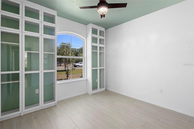 empty room with a ceiling fan and baseboards