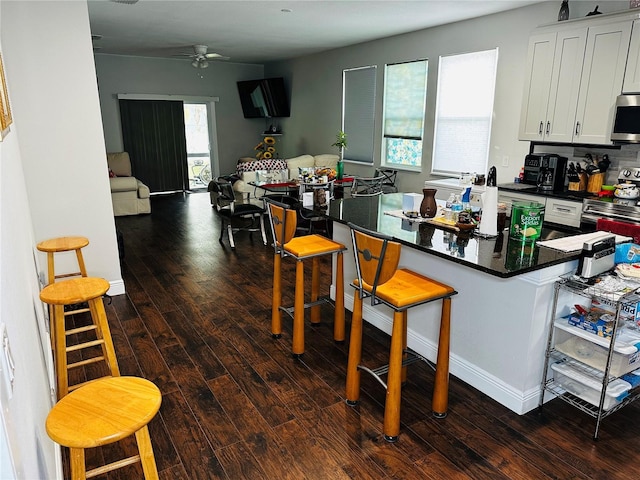 606 W Voorhis Ave, Deland, FL 32720 - kitchen featuring dark wood-type flooring, dark countertops, a kitchen breakfast bar, and stainless steel appliances