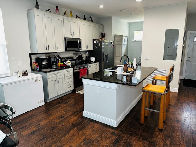 606 W Voorhis Ave, Deland, FL 32720 - kitchen with dark wood finished floors, dark countertops, a sink, electric panel, and appliances with stainless steel finishes