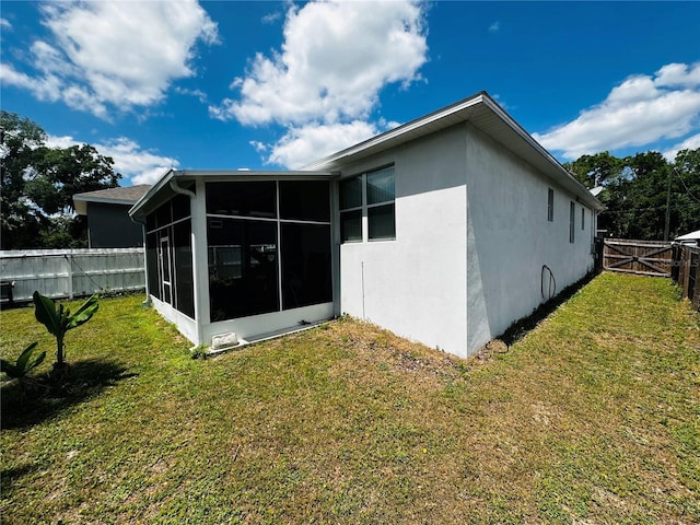 606 W Voorhis Ave, Deland, FL 32720 - rear view of house with stucco siding, a sunroom, a fenced backyard, and a lawn